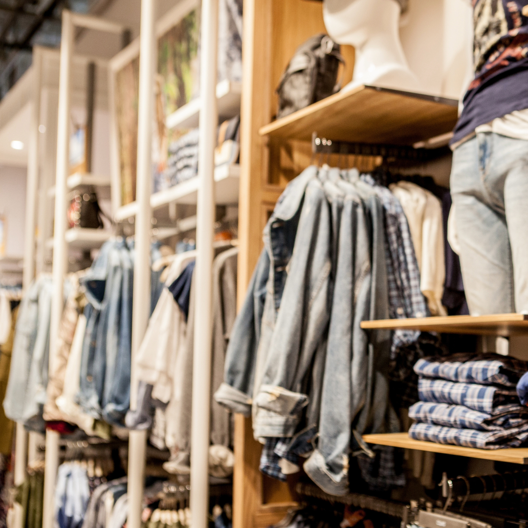 Clothing racks stalked with clothes inside of a store.